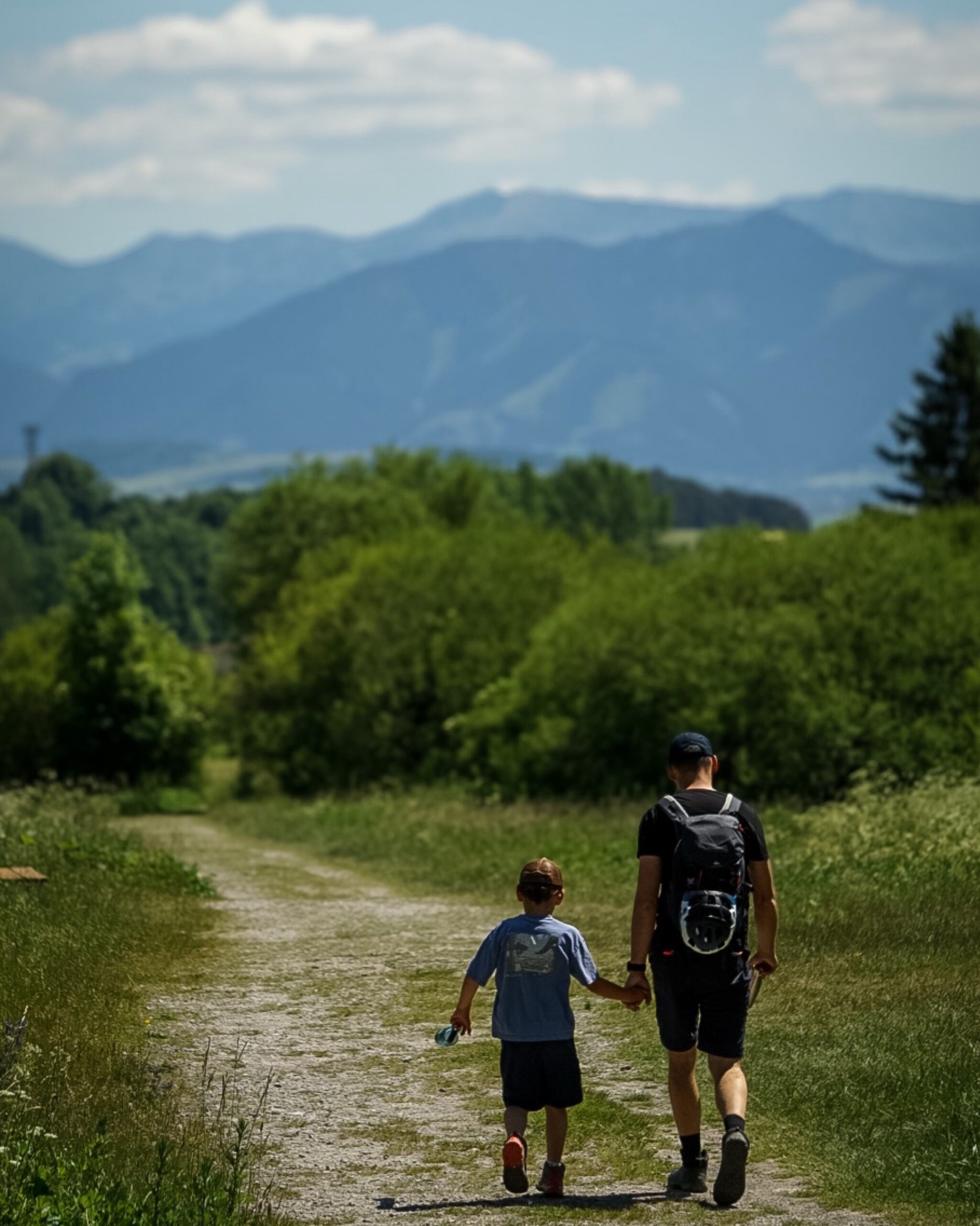 Ojciec i syn idą szlakiem w Dolinie Prosieckiej, w tle góry Tatr Niskich